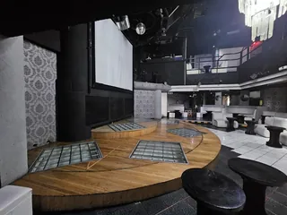 Pista de baile de duela con paneles de vidrio iluminados y la pantalla de proyección al fondo