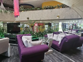 Sofás de terciopelo morado y butacas blancas bajo las velas de tela del techo